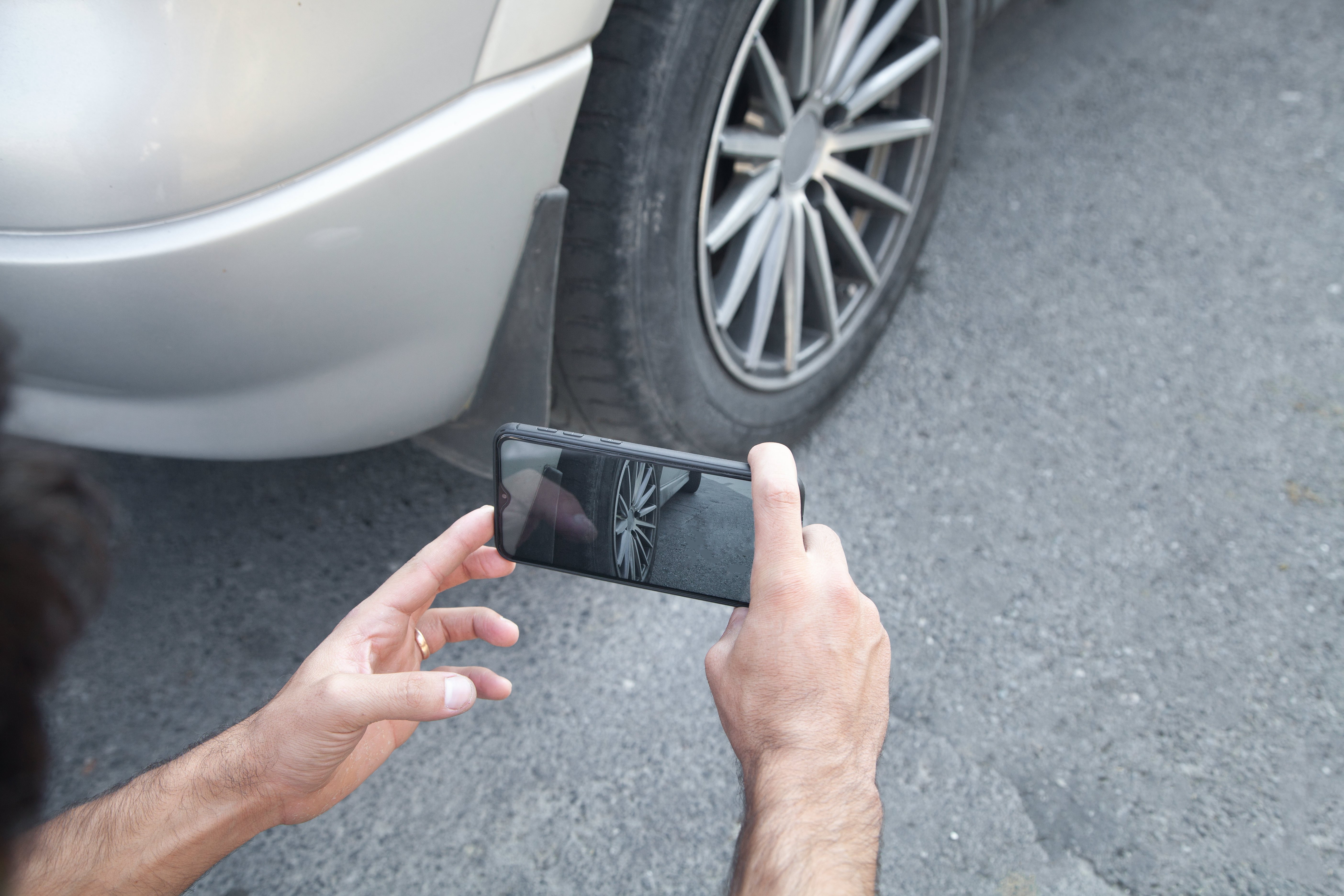 Osoba robiąca zdjęcie koła samochodu na swoim telefonie